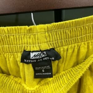 Greenish yellow skirt with elastic waist and wooden button detail. Size Small.